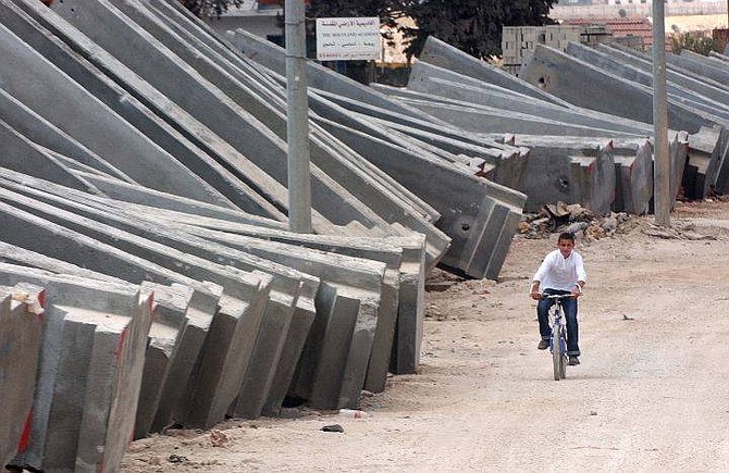 A Palestinian boy rides his bicycle next to cement blocks to be used in the construction of a section of Israel&#039;s separation barrier in the town of A-Ram, in the outskirts of Jerusalem, Friday July 9, 2004. The U.N.&#039;s highest judicial authority decided  Israel&#039;s planned 425-mile-long barrier in the West Bank violates international  law and must be dismantled.  Palestinians called the decision ``historic,&#039;&#039;  while Israel rejected the world court&#039;s authority in judging the matter.(AP Photo/Muhammed Muheisen)
