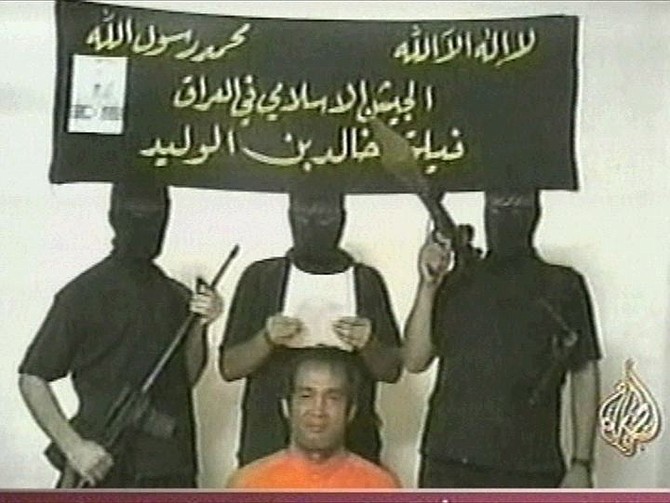 This is an image taken from footage by pan-Arab TV channel Al-Jazeera broadcast Wednesday July 7, 2004, purporting to show armed men reading a statement with a Filipino hostage wearing orange. The Banner behind has the name of the armed group &quot;Iraqi Islamic Army - Khaled bin al-Waleed corps&quot;.  Al-Jazeera logo below right. (AP Photo/APTN, Al-Jazeera TV) ** TV OUT **
