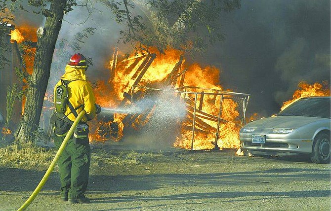 Cathleen Allison/Nevada AppealA firefighters battles a blaze that engulfed a home on Curry Street Wednesday,.
