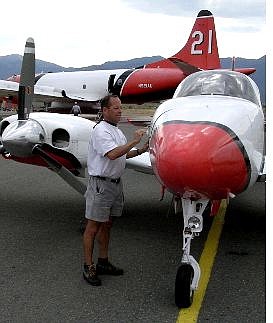 Photo by Karl HoreisUnited States Forest Service lead plane pilot Greg McDonald of Ogden, Utah, secures a compartment Friday on the twin-engine Beechcraft he uses to escort heavy air tankers like the P-3 Orion seen in the background to their drop zones.