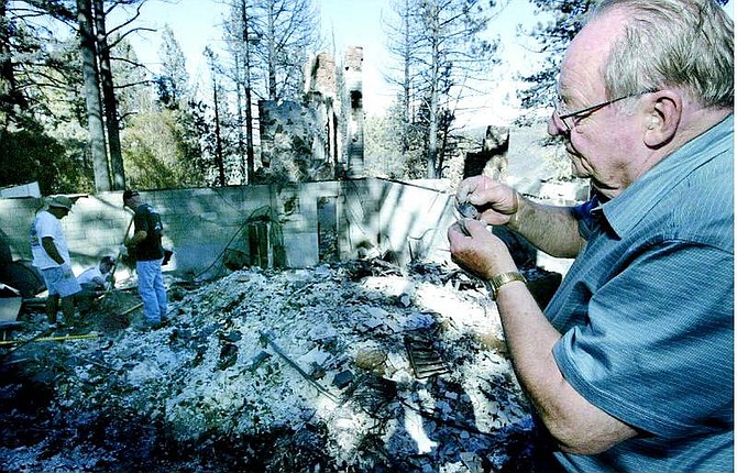Cathleen Allison/Nevada Appeal Ted Stokes looks at his burned WWII dog tags as his family and friends sift through the rubble of his Kings Canyon home Monday afternoon.