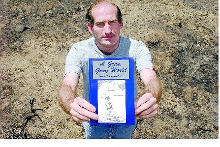 Budding author Ryan J. Cunningham holds his book  &#039;A Gray Gray World&#039; at an area burned by the Waterfall fire.  Cunningham will donate a book to every family that lost a home to the fire and half the  proceeds from book sales to victims of the fire.   Rick Gunn Nevada Appeal
