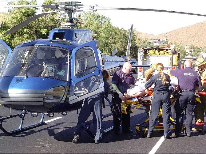 Photo by Trooper Chuck Allen Emergency workers load a Carson City man into a Care Flight helicopter Monday afternoon following an accident in Pleasant Valley.