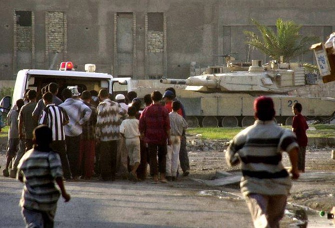 An American tank stands by as the crew allow time for an ambulance to pick up a Mahdi army injured man and another casualty from the fighting between  Al-Sadr&#039;s men with U.S. troops in the Baghdad neighbourhood of Sadr City, Iraq Thursday Aug. 5, 2004. Insurgents loyal to radical Shiite cleric Muqtada al-Sadr fought fierce clashes Thursday with U.S. and Iraqi forces in the holy city of Najaf that quickly spread to other Shiite areas. (AP Photo/Mohammed Uraibi)
