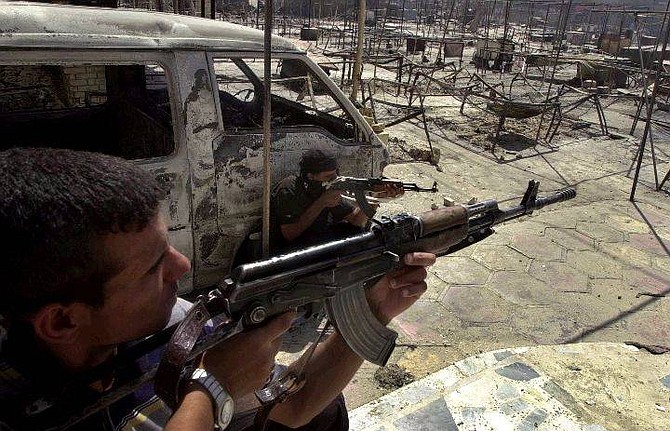 Fighters loyal to radical Shiite cleric Muqtada al-Sadr  aim their Kalashnikovs during clashes with U.S. forces and Iraqi National guards in the holy Muslim city of  Najaf, 100 miles (160 kilometers) south of Baghdad, Iraq Saturday Aug. 7, 2004. Sporadic explosions and gunfire echoed through the holy Shiite city of Najaf on Saturday after two days of intense clashes between U.S. forces and Shiite Muslim insurgents that marked some of the bloodiest fighting in Iraq in months.  (AP Photo/Hadi Mizban)