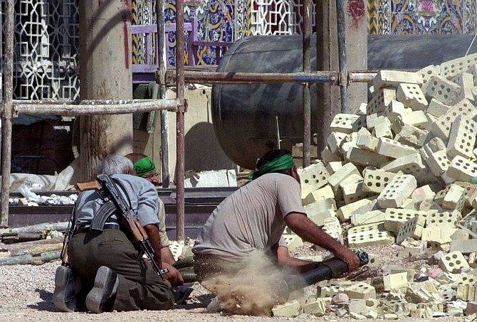 Insurgents fire a weapon in the holy city of Najaf, southern Iraq Wednesday Aug. 11, 2004. Fighting in Najaf entered its seventh day, with Iraqi police manning checkpoints that cut the holy city in two. No U.S. casualties were reported in the fighting, which took place near the Imam Ali shrine, one of the holiest in Shia Islam. (AP Photo/Hadi Mizban)