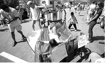 Brad Horn/Nevada Appeal Camille Vecchiarelli, of Dayton, relaxes after her bed broke before the start of the outhouse races on Pike Street during the Santa Maria Day festival on Saturday. Her pushers from left, Oscar Turnipseed and Russ Harig, of Dayton, get ready for another try.