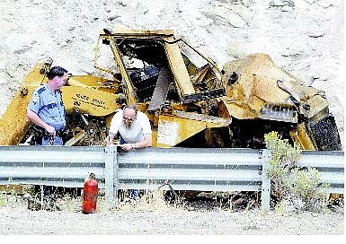 Dan Thrift/Appeal News Service John Heizer writes a report after the bulldozer he was using fell about 150 feet off a cliff on Monday afternoon. The mishap closed the eastbound lane of Highway 50 for more than two hours. Heizer was unhurt after he jump off the dozer before it fell.