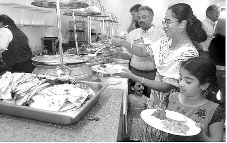 Rick Gunn/Nevada Appeal Raghavi Anand, 8, bottom right, and her mother Ratna Anand, behind her, dish up a plate of Indian cuisine during the grand opening of India Curry Restaurant in the former Godfather&#039;s Pizza restaurant on North Carson Street. The owners offered a free taste of their dishes Wednesday.