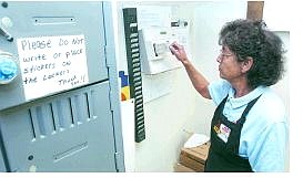 Rick Gunn/Nevada Appeal Grocery Outlet clerk Millie Hansen punches the time clock Friday afternoon.
