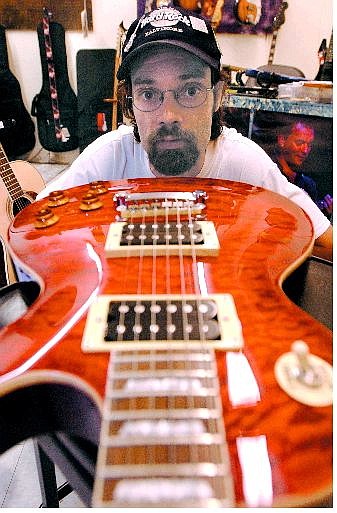 Cornerstone Music Store owner Troy D. White looks down the body of an Epiphone Red Flametop Les Paul guitar at his music store on Friday. The store carries public address gear, CDs, sheet music and can order band  instruments.                              Rick Gunn/Nevada Appeal
