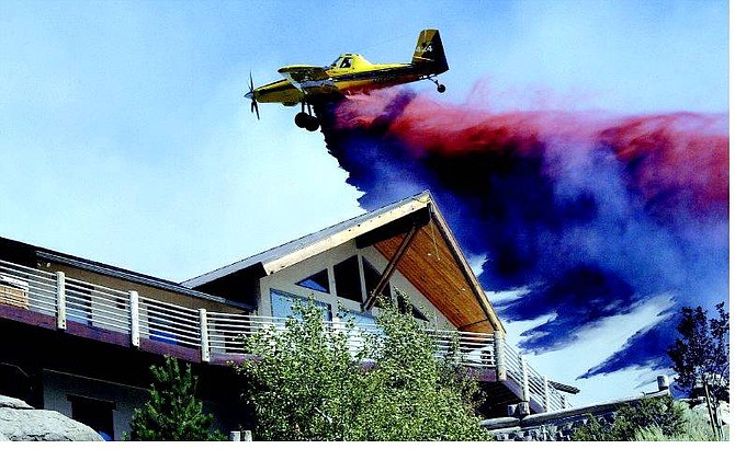 Cathleen Allison/Nevada Appeal A single-engine air tanker makes a drop on a house at the end of Chance Lane in Pleasant Valley Wednesday afternoon as firefighters fight the 2,500-acre Andrew fire.