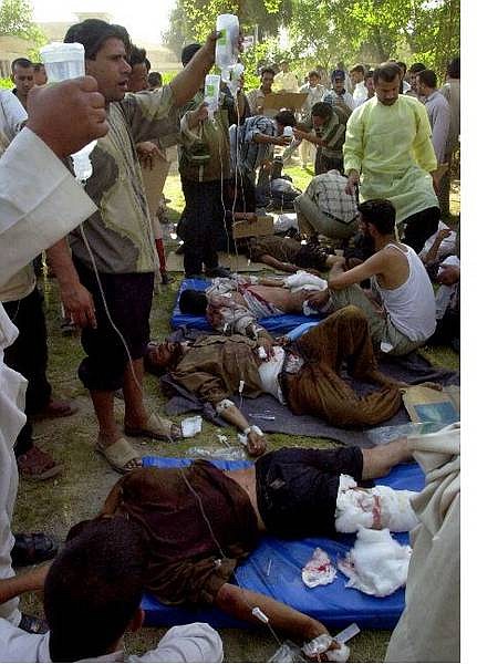 Iraqi men tend to the injured from a mortar attack on the main mosque in the Iraqi city of Kufa, after the hospital ran out of space to treat the patients, in the garden of a hospital in Kufa, Iraq Thursday Aug. 26, 2004. The mortar barrage hit killed 27 people and wounded 63 others as they prepared to march on the violence-wracked city of Najaf.  (AP Photo/Hadi Mizban)
