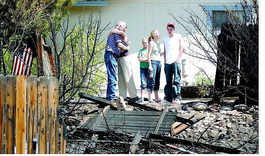 BRAD HORN/Nevada Appeal Charles Ingraham hugs his daughter Cheryl Mothershead of Elko while his grandchildren Travis, 16, Brandy Pagni and Rachael Ingraham, 16, look at the remains of Brent Danner&#039;s home at 2810 Ramona Thursday. Ingraham&#039;s home missed disaster when the Andrew fire swept through the hills south of Reno on Wednesday.