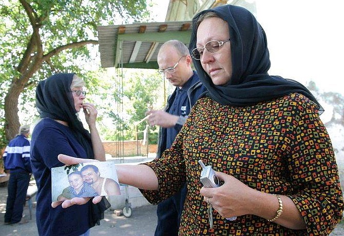 Larisa Polyakov holds a picture of her husband Vladimir and daughter, no name provided, outside a morgue in Kamentsk-Shakhtinsky, Russia, in the Rostov region some 600 miles south of Moscow, Friday, Aug. 27, 2004, after Vladimir died in a plane crash Tuesday. Vladimir Polyakov&#039;s relatives arrived in Kamenetsk-Shakhtinsky to retrieve his coffin and bring it to Moscow for burial. Polyakov&#039;s sister Marina, left, and brother Yuri, speak in the background. (AP Photo/ Sergei Venuavsky)