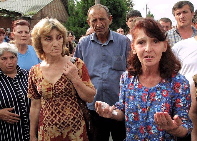 Ossetian women try to get news about their children, as they stand not far from the school seized by attackers in Beslan, North Ossetia, Wednesday, Sept. 1, 2004. Attackers wearing suicide-bomb belts seized a Russian school in a region bordering Chechnya on Wednesday, taking hostage about 400 people, half of them children, and threatening to blow up the building. At least two people were killed, one of them a parent who resisted an attacker. (AP Photo/Musa Sadulayev)