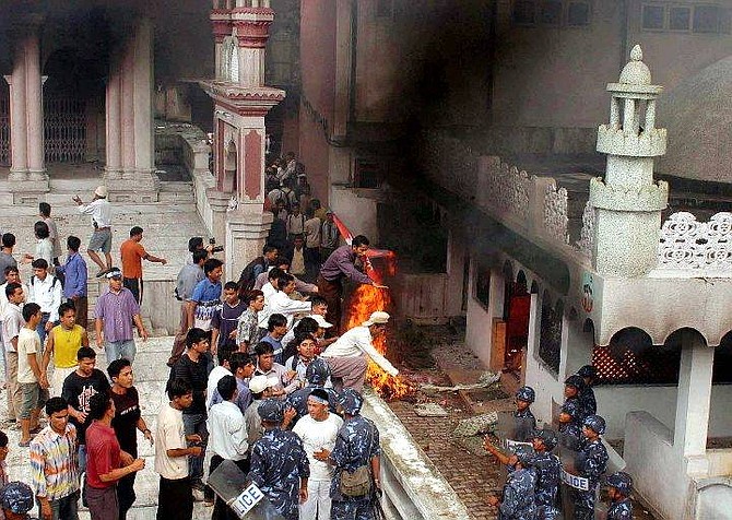 Riot Policemen, right, try to prevent protestors from entering into a burning mosque in Katmandu, Nepal, Wednesday, Sept.1, 2004. Thousands of demonstrators ransacked a mosque and clashed with police in the Nepalese capital to protest the killing of 12 Nepalese hostages by Iraqi militants. (AP Photo/Binod Joshi)