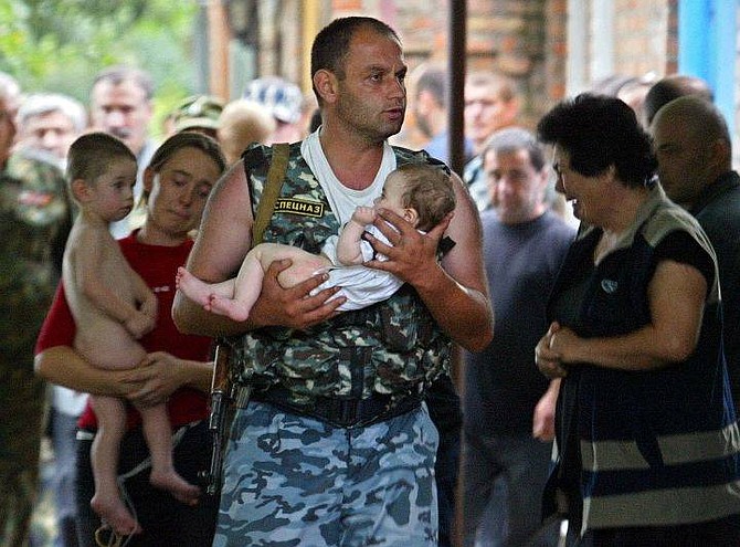 A special forces soldier carries a baby  as a woman follows carrying a child after being released by militants in Beslan, North Ossetia, Thursday, Sept. 2, 2004. Heavily-armed militants released at least 31 women and children on Thursday from the provincial Russian school where they are holding more than 350 hostages for the second straight day, officials said. (AP Photo/Sergey Ponomarev)