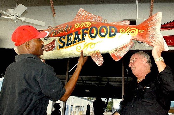 Louis Gene, left, and Jack Miller, right, owner of the Jupiter Ale House, take down a decorative wooden fish that was hanging above the eatery&#039;s outdoor deck as they prepare for the arrival of Hurricane Frances, Thursday, Sept. 2, 2004, in Jupiter, Fla. (AP Photo/Rick Silva)