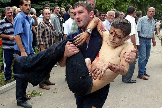 A wounded boy is carried after he escaped from a school in Beslan, Northern Ossetia, Russia Friday, Sept. 3, 2004. Four children and a woman were killed as commandos stormed a school Friday in southern Russia where hundreds of hostages had been held for three days by Chechen rebels strapped with explosives. Local officials said 250 hostages were wounded, 180 of them children. (AP Photo/Ivan Sekretarev)
