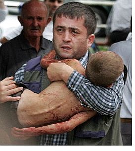 Associated Press A man carries an injured child who escaped from a seized school in Beslan, North Ossetia, on Friday.