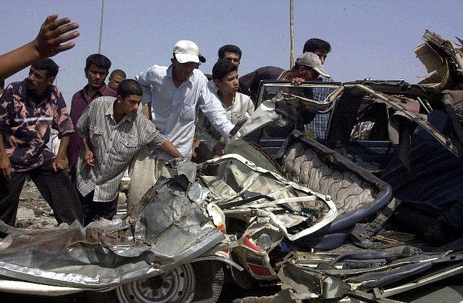 Residents of Sadr City show cars that were run over by U.S. armored vehicles, Baghdad, Iraq, Tuesday Sept. 7, 2004.  U.S. forces battled radical Shiite cleric Muqtada al-Sadr&#039;s supporters in the Baghdad slum on Tuesday, killing at least 34 people, including one American soldier, and injuring 193. (AP Photo/Karim Kadim)