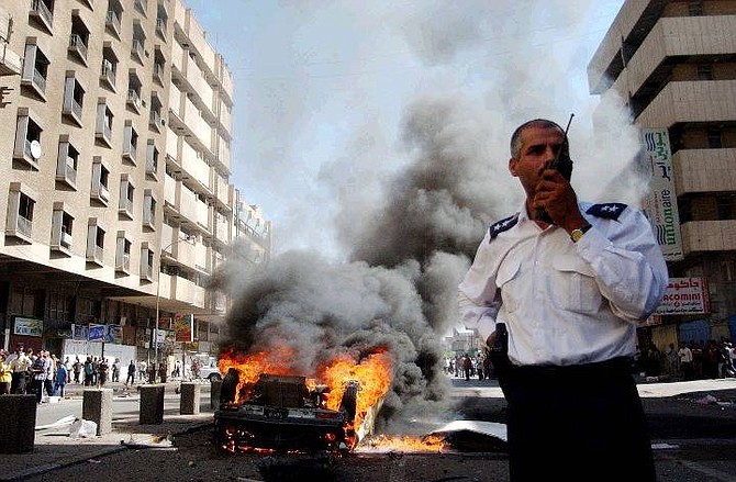 An Iraqi police officer calls for help to put out the fire after a car bomb explosion in central Baghdad, Iraq, Tuesday Sept. 14, 2004. A suicide bomber detonated himself on a busy street killing himself and injuring one pedestrian. (AP Photo/Khalid Mohammed)