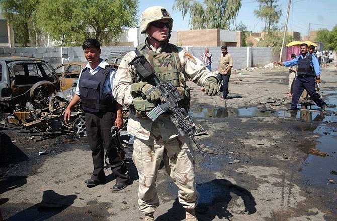 A U.S. soldier inspects the site along with Iraqi policemen after a massive explosion outside a police station at the end of Haifa Street in Baghdad, Iraq, Tuesday Sept. 14, 2004. At least 47 people were killed and 114 wounded as the blast ripped through scores of people gathered there hoping to join the police force. (AP Photo/Khalid Mohammed)