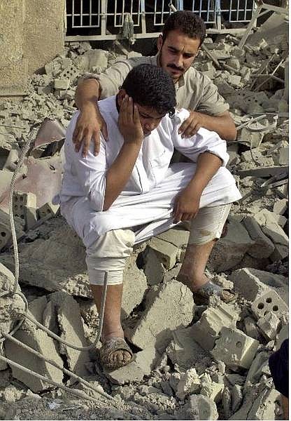 Iraqi men comfort each other as they sit in the rubble of their destroyed house in Fallujah, outside Baghdad, Iraq, Monday, Oct. 18, 2004 after U.S. troops pounded the insurgent stronghold of Fallujah with airstrikes and tank fire overnight. (AP Photo/Mohammed Khodor)