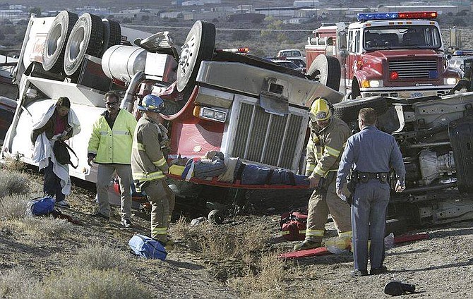 Cathleen Allison/Nevada AppealCentral Lyon County Fire personnel tend to an injured man following an accident on Hwy. 50 east of Mound House.  The Cinderlite semi-truck was hauling three trailers of sand, much of which spilled onto the highway Monday afternoon.