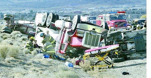 Cathleen Allison/Nevada Appeal Central Lyon County Fire personnel tend to an injured man following an accident on Highway 50 east of Mound House. A Cinderlite semi-truck was hauling three trailers of sand, much of which spilled onto the highway Monday afternoon.