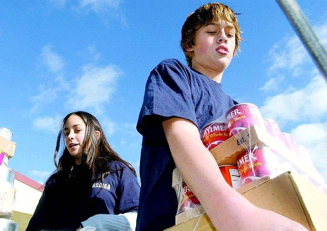 Rick Gunn/Nevada Appeal Carson Middle School students Annika Chryssos, 13, and Levi Masterson, 13, load canned goods on the FISH truck Wednesday at the school.
