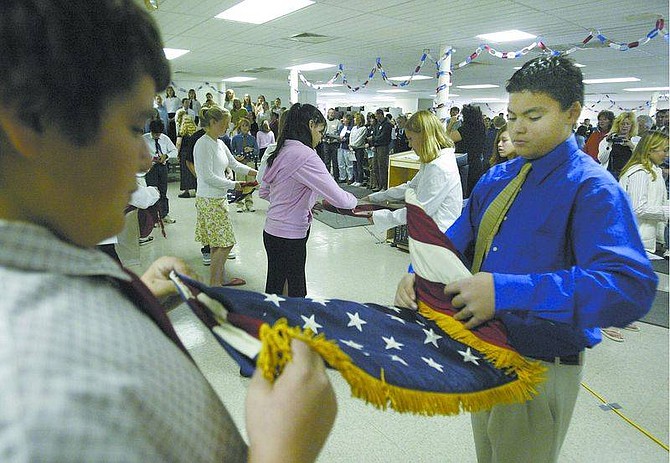 Cathleen Allison/Nevada AppealCarson Middle School eighth-graders A.J. Evans, left, and James Patten, both 13, participate in a flag-retirement ceremony and Veterans Day Commemoration on Wednesday at the school.