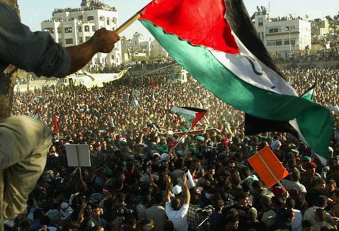 The coffin of Yasser Arafat is carried through a crowd of Palestinian mourners to be lowered into his grave at his compound in the West Bank town of Ramallah Friday Nov 12, 2004. (AP Photo/David Guttenfelder)