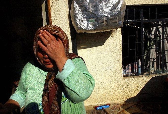 Iraqi woman cries outside her home home after a suicide car bomb exploded nearby and blown off her windows, in Baghdad Sunday Nov. 28, 2004.  (AP Photo/Hadi Mizban)