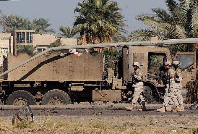 US soldiers examine the scene after an US military truck was damaged in suicide car bomber attack on Baghdad&#039;s airport highway Tuesday Nov. 30, 2004. The highway linking Baghdad to the city&#039;s international airport is considered one of the most dangerous roads in Iraq.There were no immediate official reports of injuries.  (AP Photo/Muhammed Uraibi)