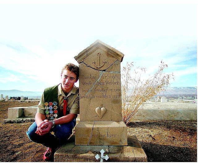 Life Scout Michael Barnes poses next to one of the head stones he repaired at the Empire Cemetery as part of his Eagle Scout project.  BRAD HORN/Nevada Appeal