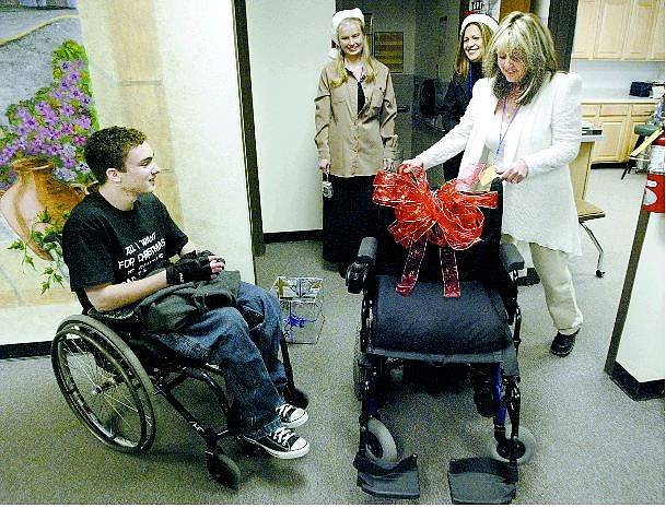 Cathleen Allison/Nevada Appeal Carson High School senior Kevin Petersen, 17, receives a new wheelchair from Capitol City Loans elves, from center, Jennifer Brooks, Maria Torres and Theresa Ohl on Friday at the high school.