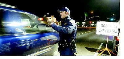 Jim Grant/Appeal News Service California Highway Patrol officer Jason Nichols waves a motorist through a sobriety checkpoint Wednesday night in South Lake Tahoe.