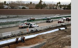Associated Press Workers take a break as rush-hour traffic drives by on the U.S. 95 widening project Dec. 27 in Las Vegas.