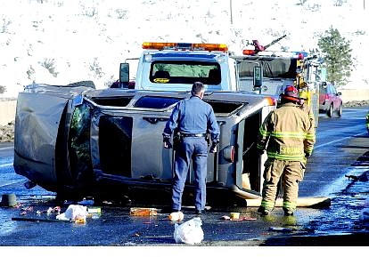 Rick Gunn/Nevada Appeal Emergency personnel work to assist a tow truck as it rights a vehicle that rolled over in the southbound lane of Highway 395 near Lakeview Hill on Wednesday.
