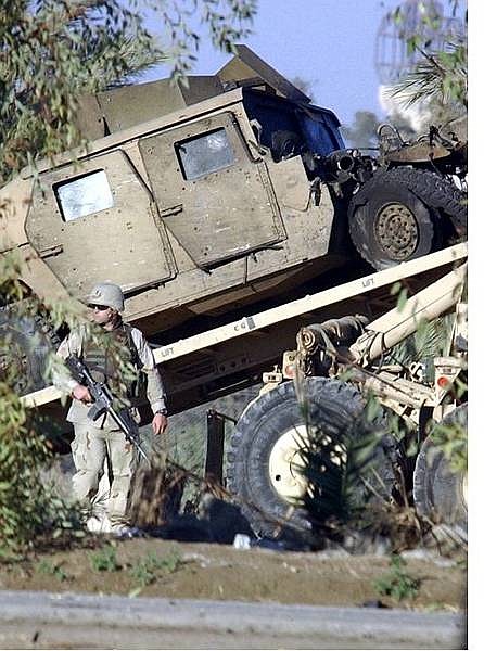 A US soldier secures the area as an armored vehicle is removed following an roadside bomb attack on a U.S. convoy on the road to Baghdad airport, Wednesday,  Jan. 26, 2005. Insurgents staged attacks against U.S. forces, schools to be used as polling stations and political party offices, as they pressed a bloody campaign to undermine Iraq&#039;s weekend elections.  (AP Photo/Mohammed Uraibi)