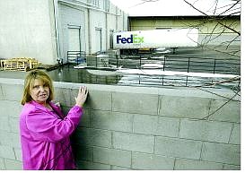 Cathleen Allison/Nevada Appeal Carson City resident Marlene Foster is upset about truck traffic and industrial noise at her home after Source Interlink Companies opened a distribution center on Kansas Street. Foster, standing on a paint bucket to peer over the 6-foot wall, wants it increased.