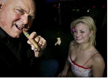 Brad Horn/Nevada Appeal Moonlite BunnyRanch owner Dennis Hof smokes a cigar at his brothel&#039;s entrance Thursday in Mound House. At right is Sierra, a prostitute at the brothel. Although county governments collect license fees, the state of Nevada has never taxed brothels. If an industry lobbying group and an anti-prostitution lawmaker have their way, that could change this year.