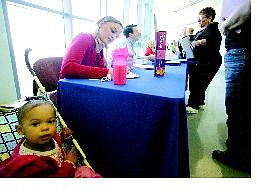 BRAD HORN/Nevada Appeal Maggie Baesman fills out an application for a teller job at Greater Nevada Credit Union while her daughter, Jalyssa Williams, 1, waits Saturday. Robert Mills, human resource representative for the credit union, center, talks with a patron during the annual job fair at Western Nevada Community College.