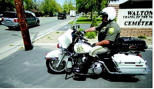 BRAD HORN/Nevada Appeal Carson City Sheriff deputy Jarrod Adams watches traffic at the corner of John and Roop Streets on Friday afternoon.