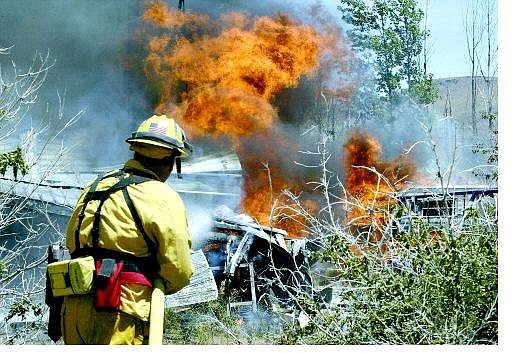 Cathleen Allison/Nevada Appeal Firefighters worked to extinguish a brush fire that consumed several vehicles and five outbuildings Wednesday in Mark Twain. Crews were able to save the primary residence, and no one was injured.