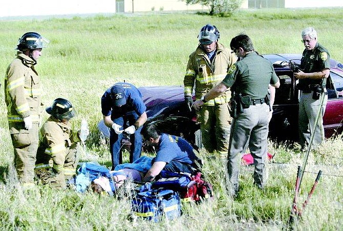 Cathleen Allison/Nevada Appeal Carson City firefighters treat a woman following a rollover accident on Fifth Street on Wednesday afternoon near the Nevada State Prison. She was taken to Washoe Medical Center by Care Flight.