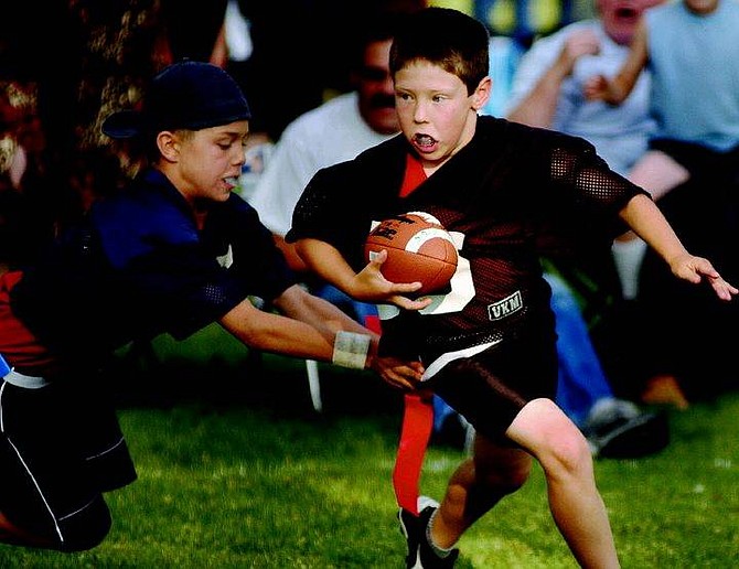 Kevin Clifford/Nevada Appeal The Raider&#039;s   Trevor Sollberger dodges a tackle from Outlaw&#039;s Tony Martini during the first half of the Carson City Youth Flag Football Leauge Division B Championship game Friday evening at Mills Park.  The Outlaws won the game 27-13.  Kevin Clifford