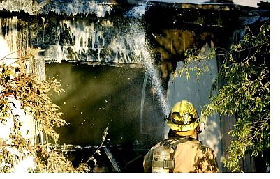 Kevin Clifford/Nevada Appeal A Carson City firefighter sprays flame-retardant on the burned house on Edmonds Drive tuesday evening to help contain the fire.